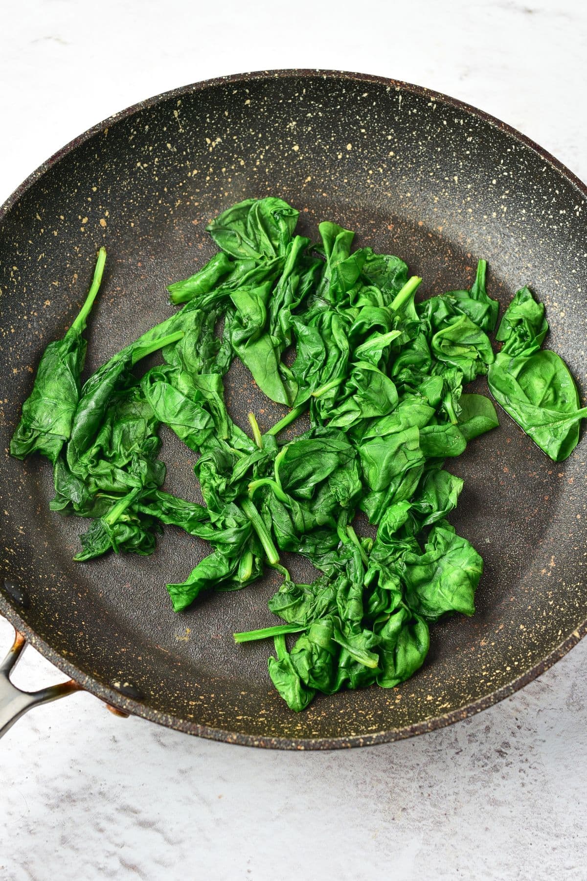 Wilted spinach leaves in skillet