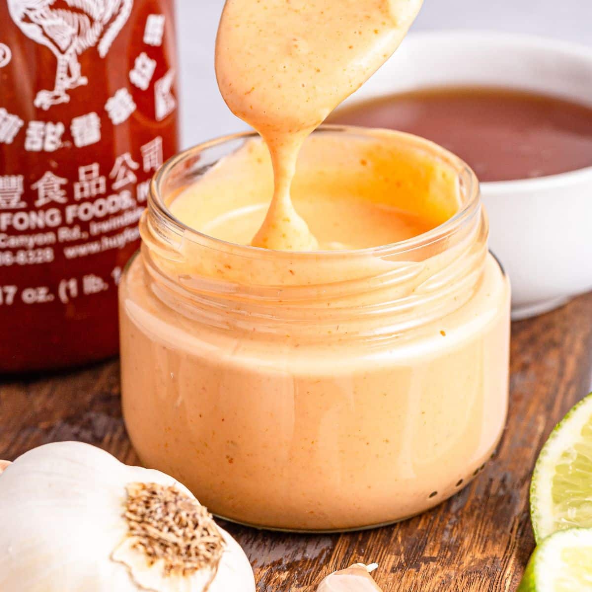 Holding up a spoonful of sriracha aioli from a jar
