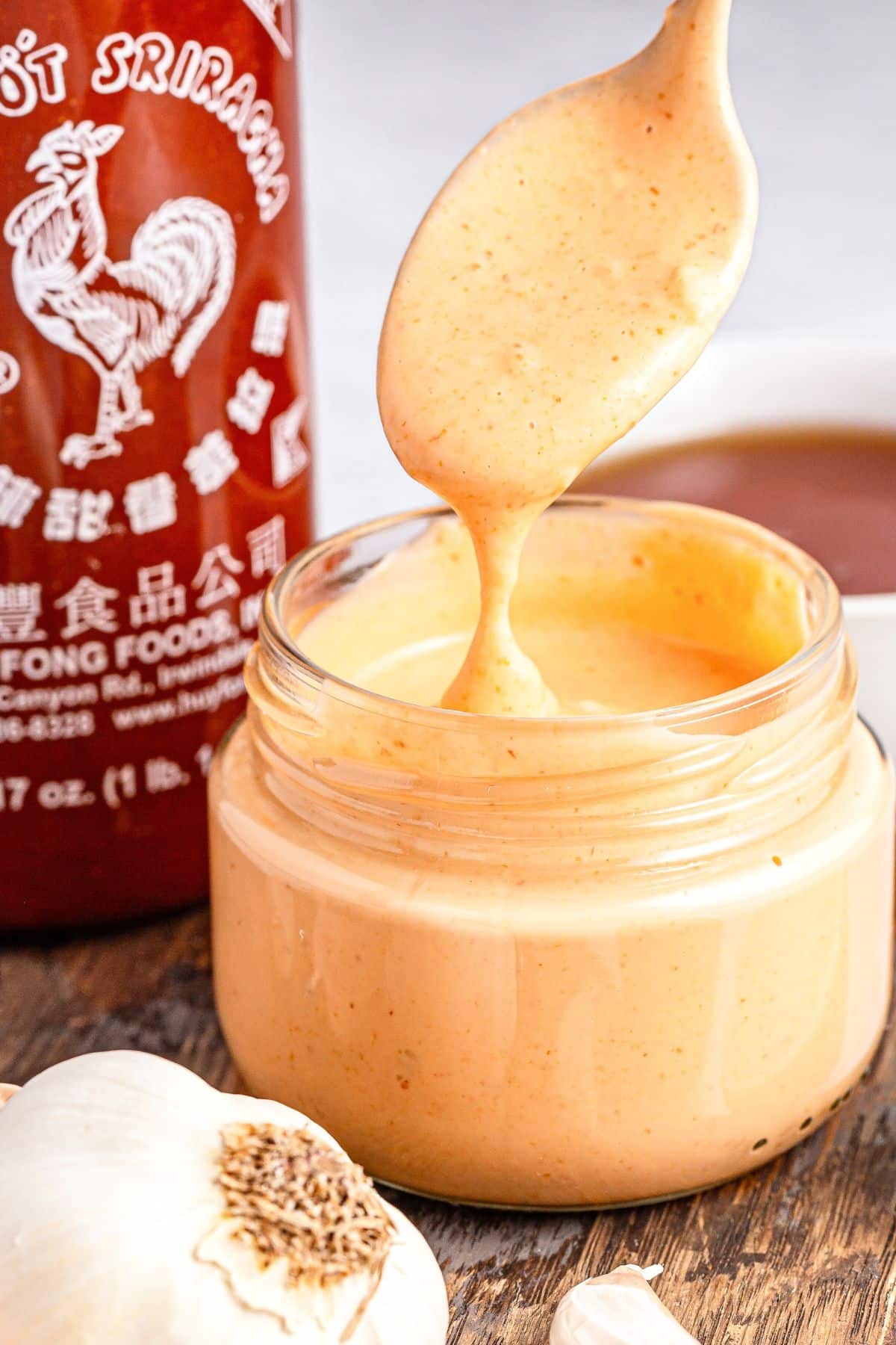 Holding up a spoonful of sriracha aioli  from a jar.