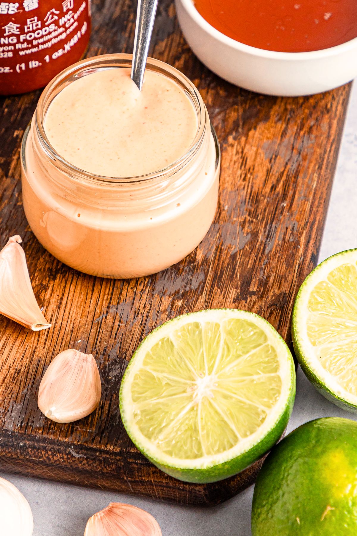 A jar of homemade sriracha aioli on wooden board.
