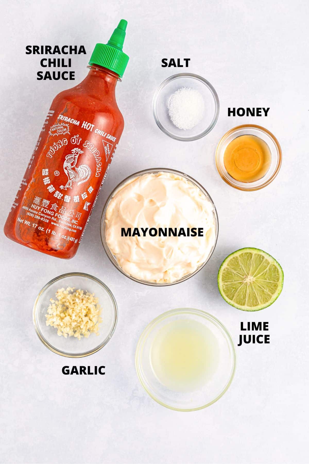 Ingredients for sriracha aioli recipe laid out on white board.