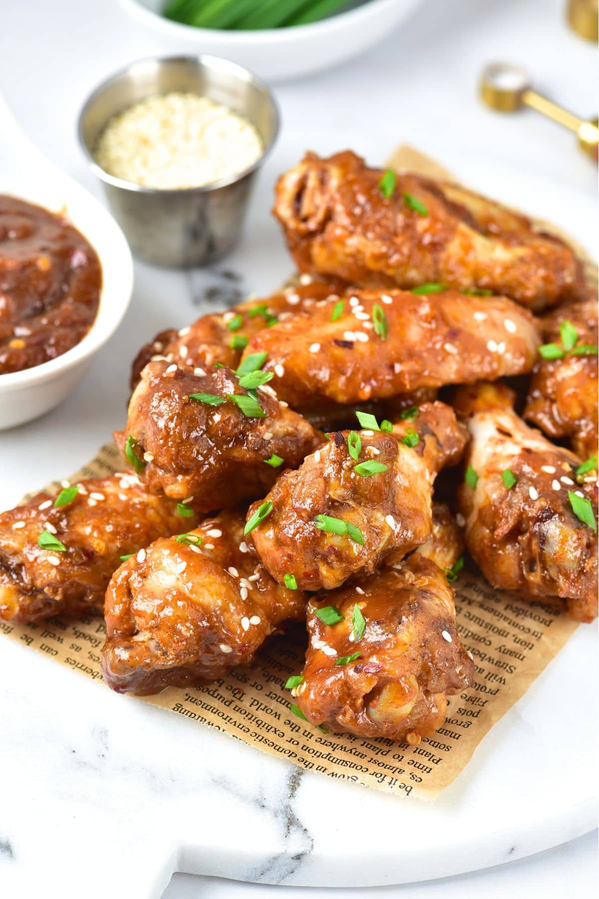 Asian sticky chicken wings on parchment-lined marble board.