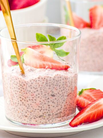 A vase of strawberry chia pudding topped with fresh strawberries.