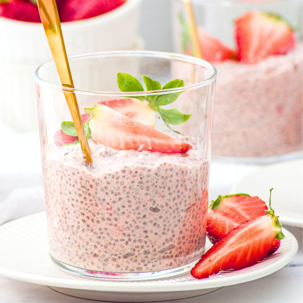 A vase of strawberry chia pudding topped with fresh strawberries.