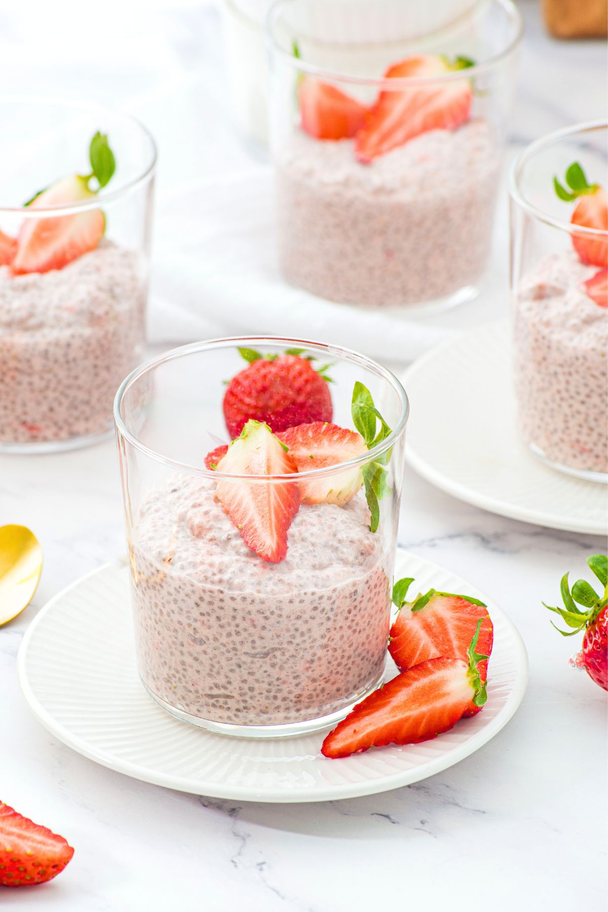 Glasses of strawberry chia pudding topped with fresh strawberries.