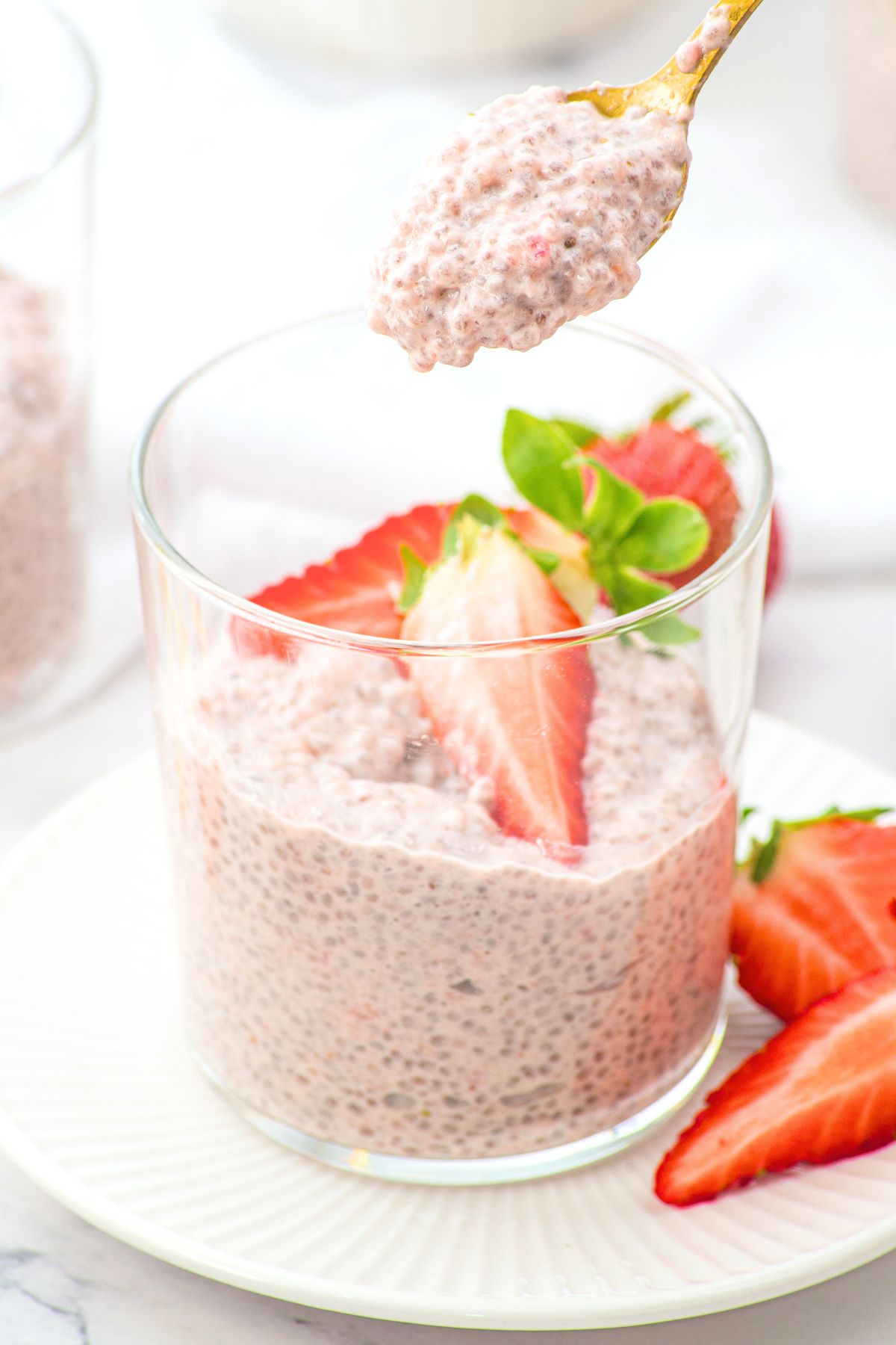 Holding up a spoonful of strawberry chia seed pudding from a glass