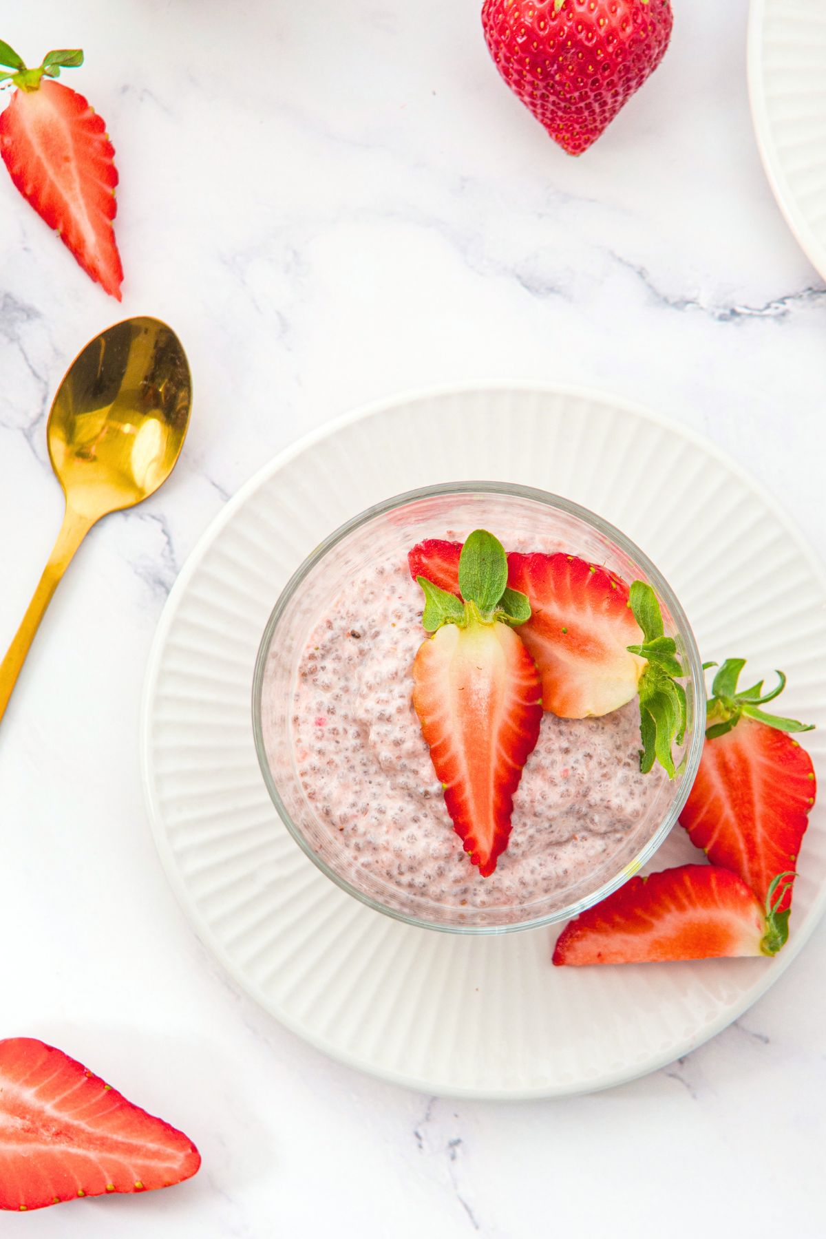 Top down view of a glass of chia strawberry pudding topped with fresh strawberries