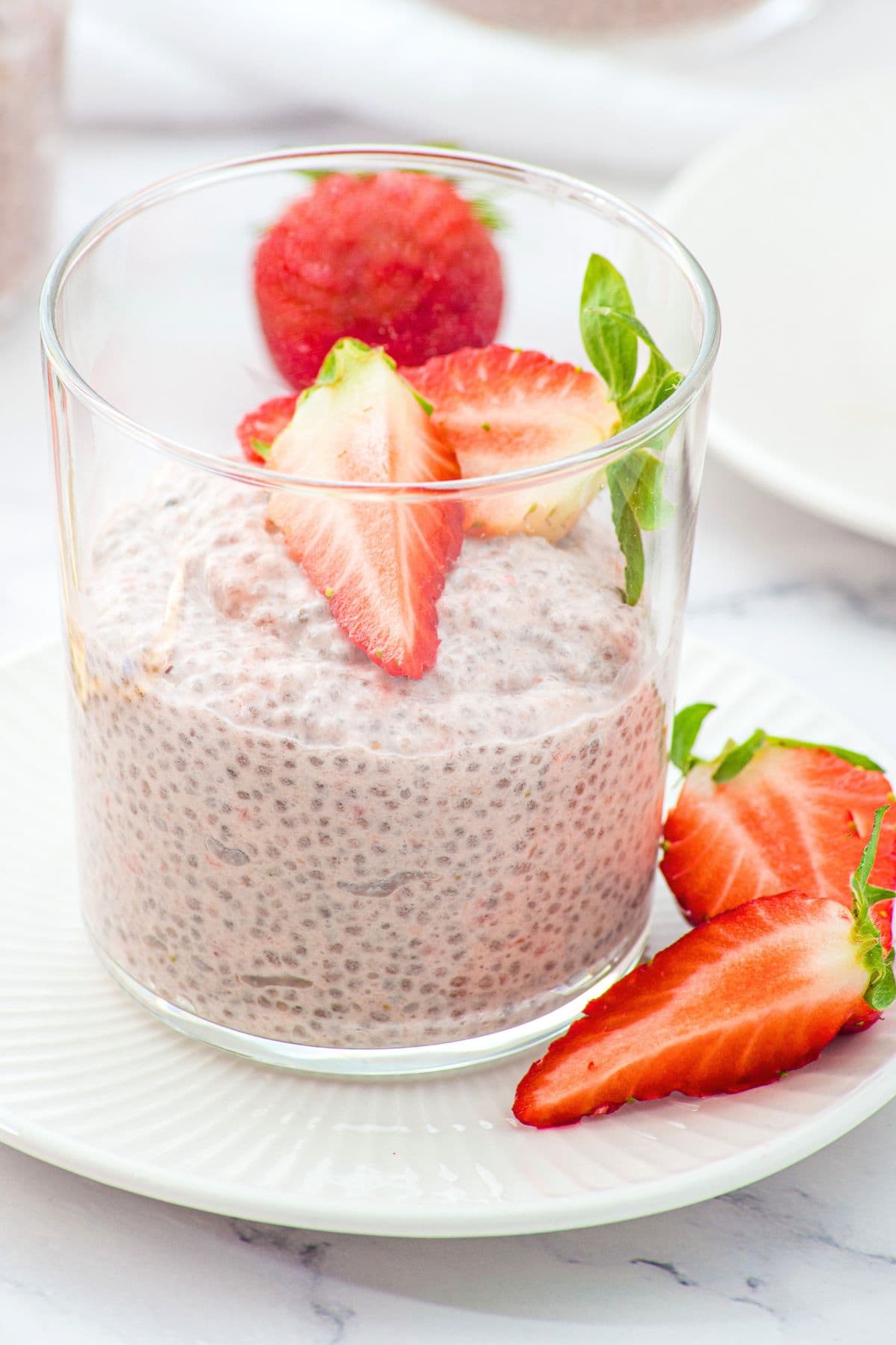 A glass of strawberry chia pudding with fresh strawberries