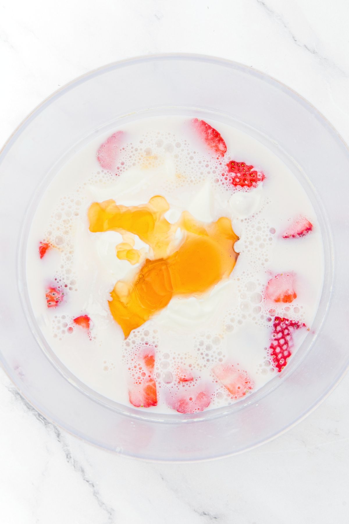 A bowl with milk, fresh strawberries, and maple syrup