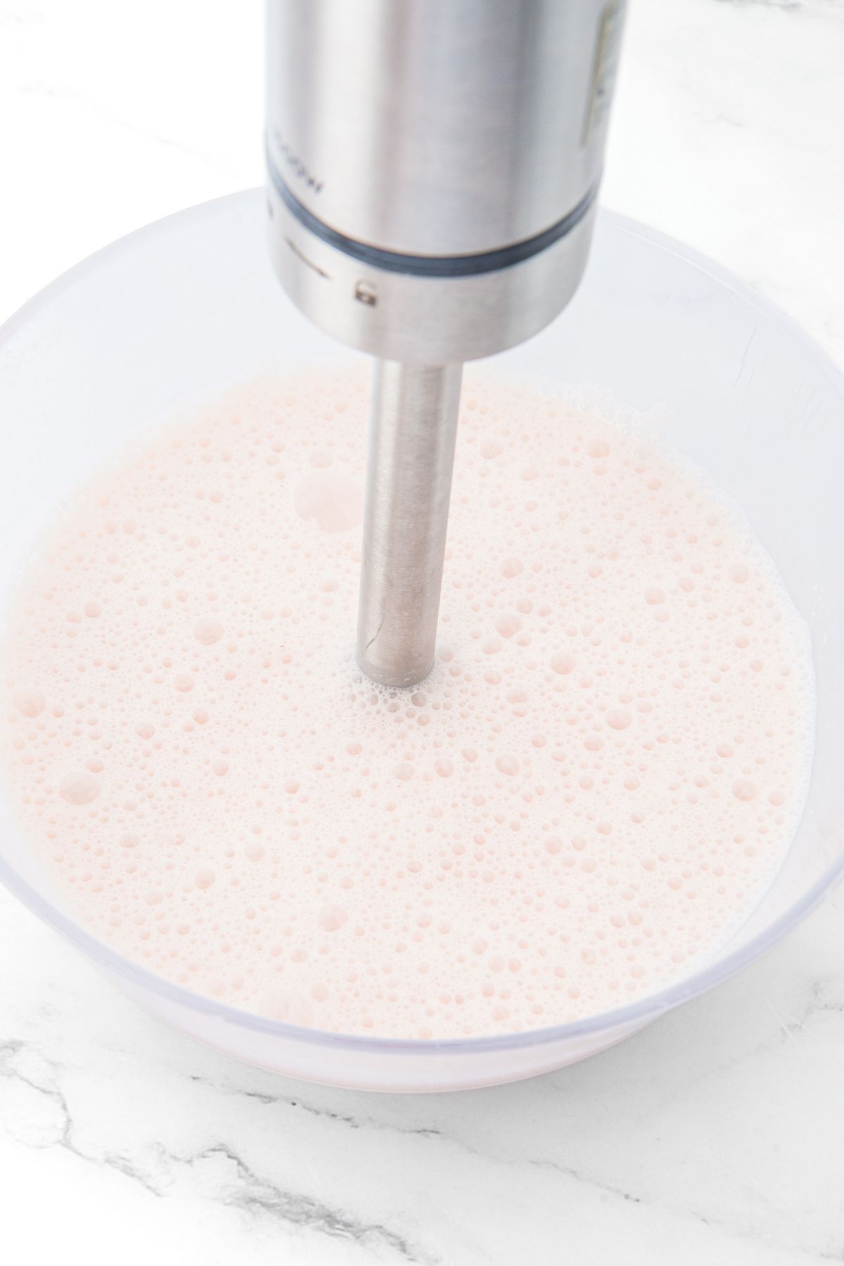 Immersion blender in a bowl with milk mixture.