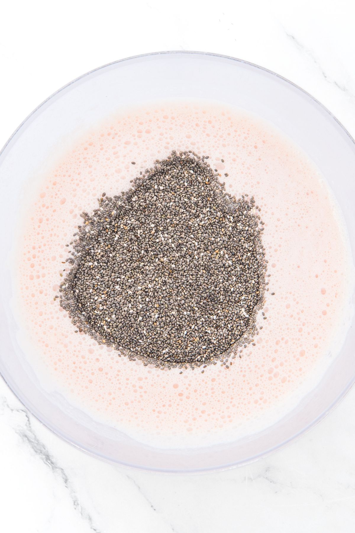 Chia seeds on top of pale pink mixture