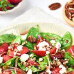 A bowl of strawberry spinach salad topped with feta cheese