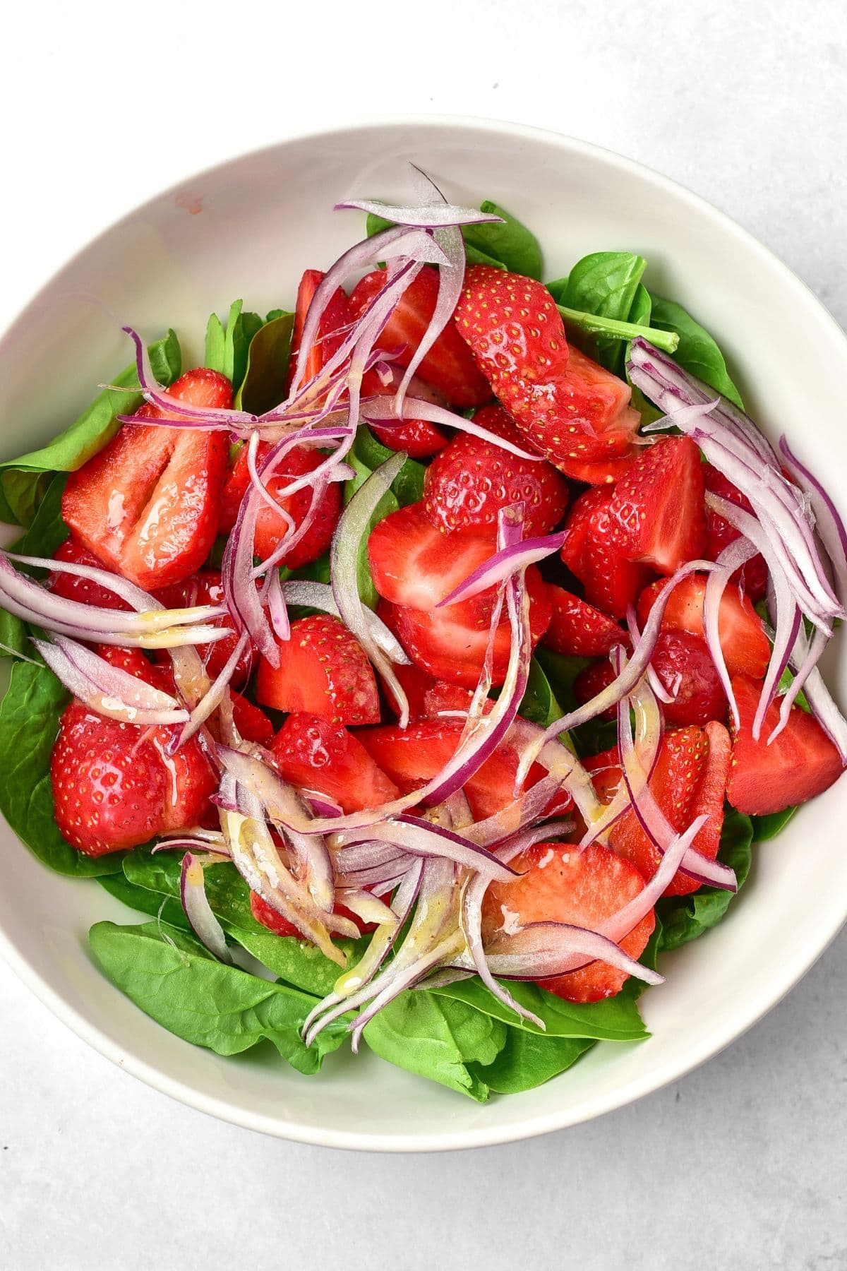 A bowl of strawberry spinach salad with balsamic dressing
