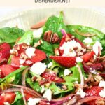 Up close view of a salad with strawberries, spinach leaves, sliced red onions and feta cheese