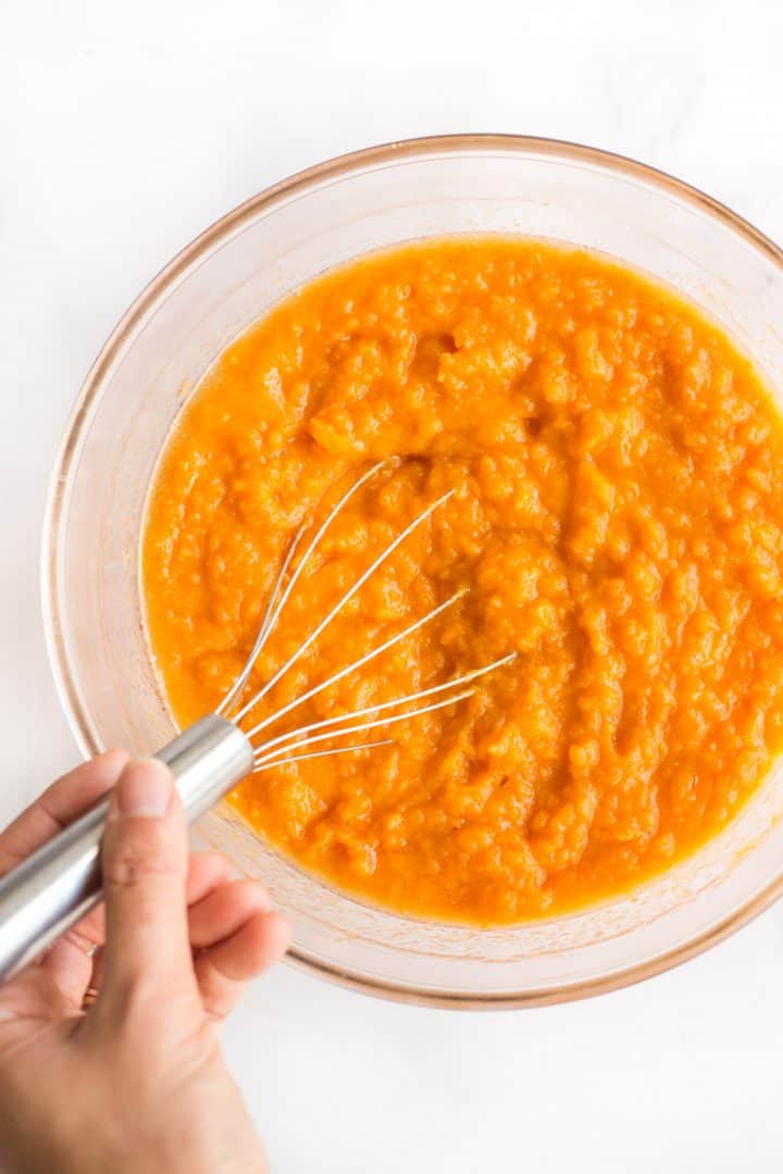 Mixing mashed sweet potatoes in glass bowl.
