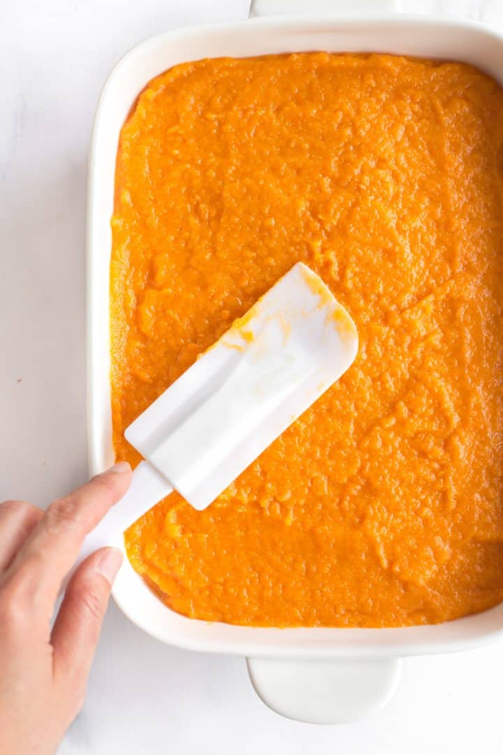 Using spatula to smooth out mashed sweet potatoes.
