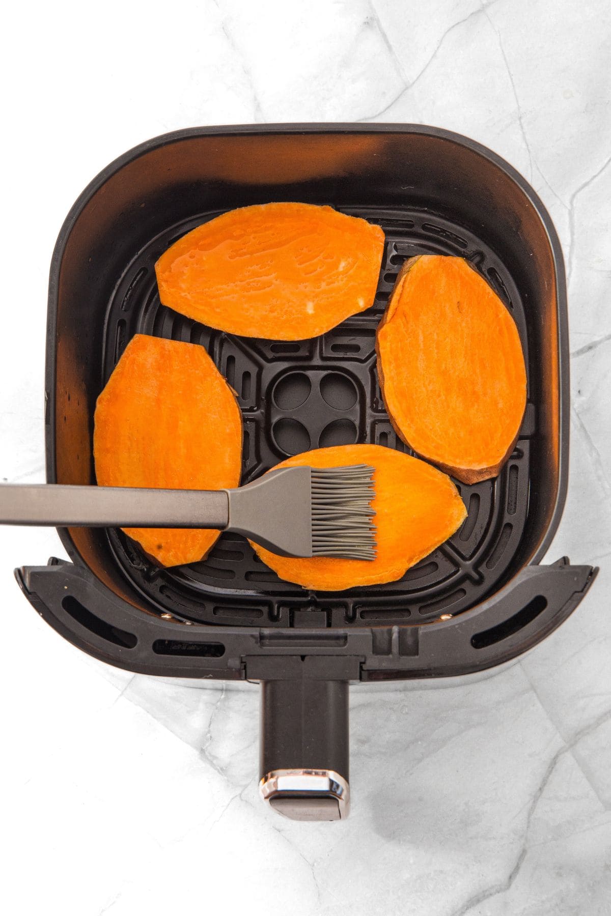 Brushing sweet potato slices with oil