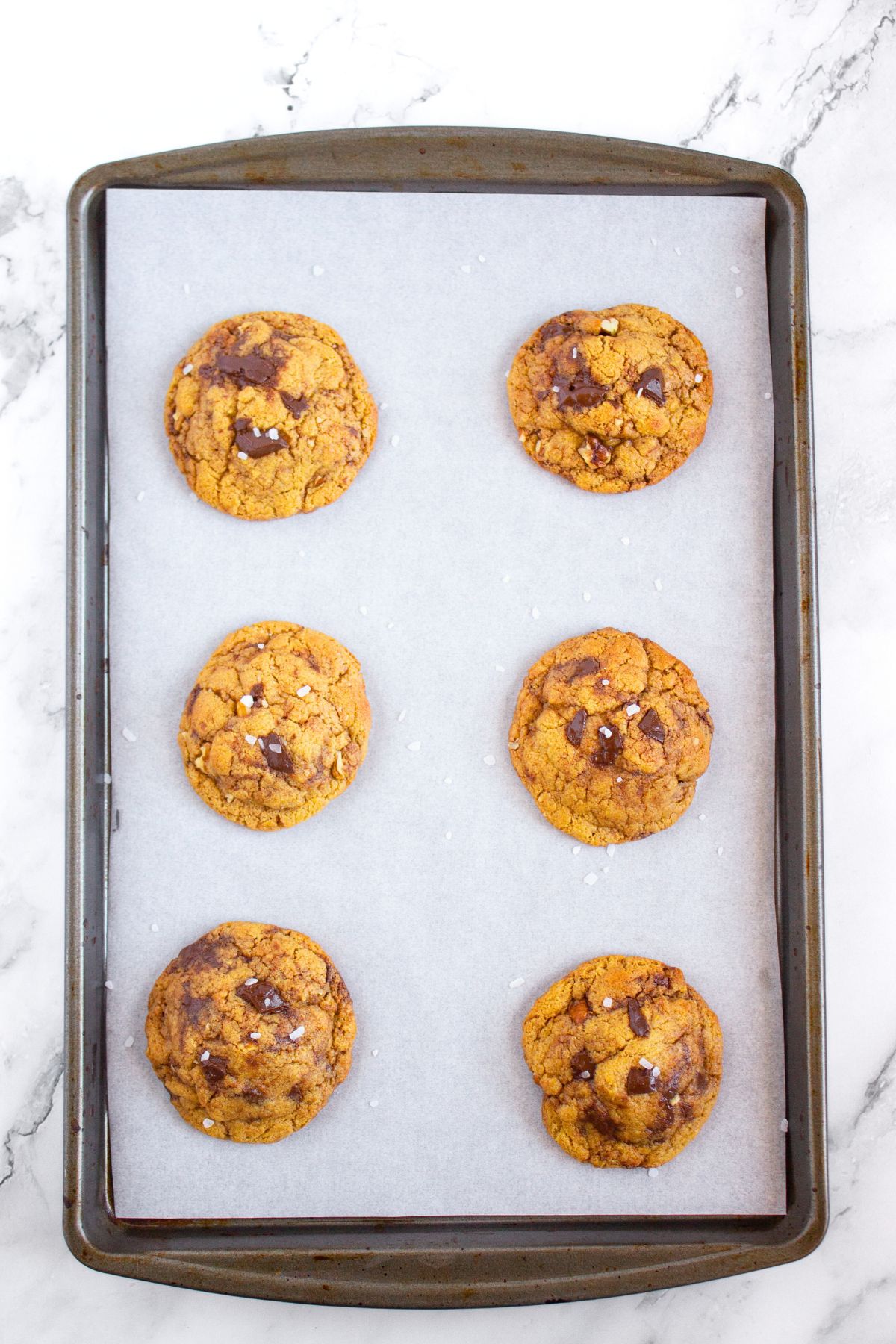 Freshly baked gluten-free tahini cookies on parchment-lined baking sheet