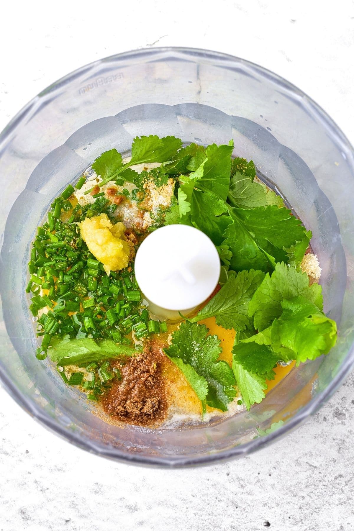 Fresh herbs, grated garlic, spices, egg and oil in food processor.