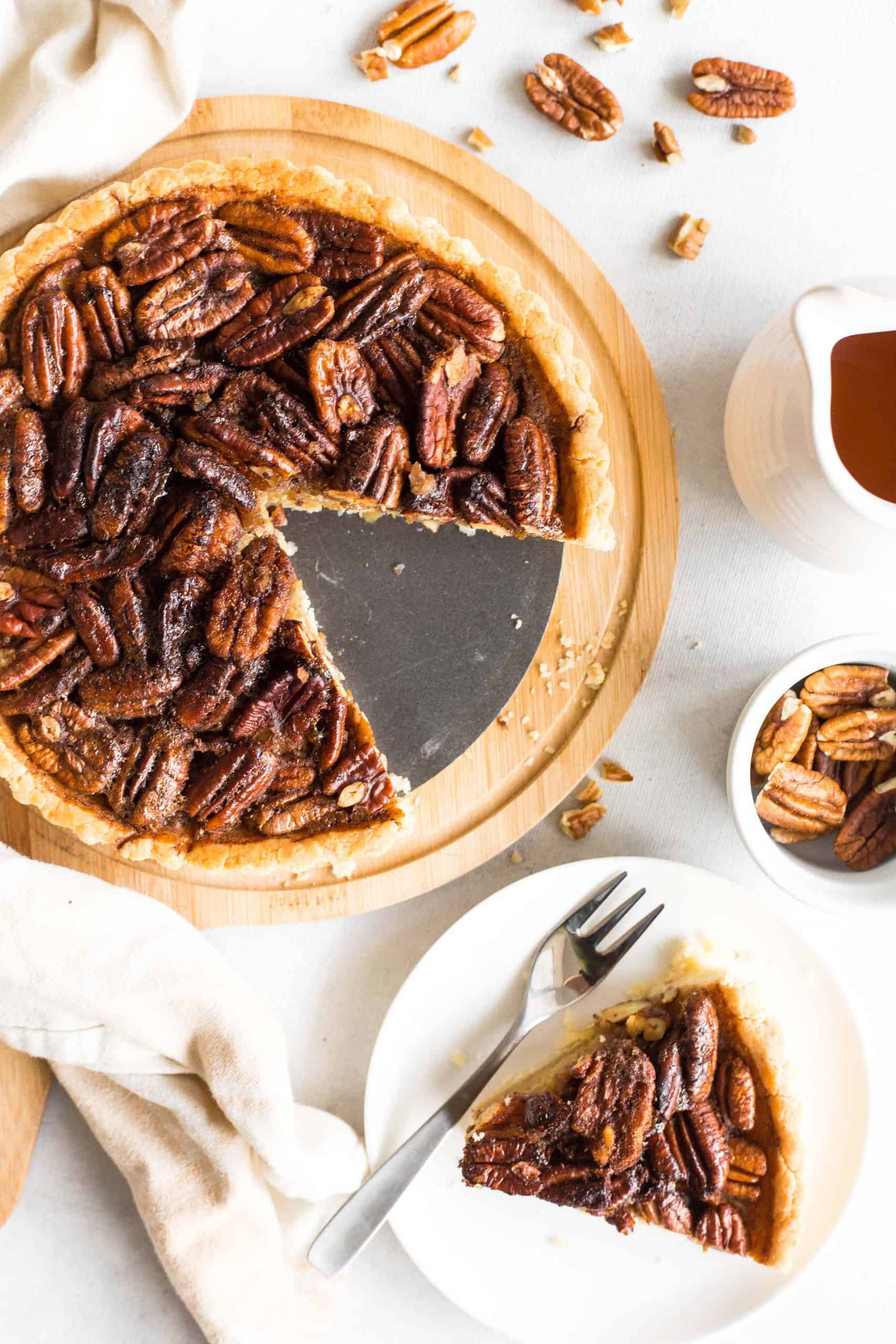 Whole pecan pie and a slice of pie on a white plate.