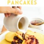 Hand pouring maple syrup over corn flour pancakes