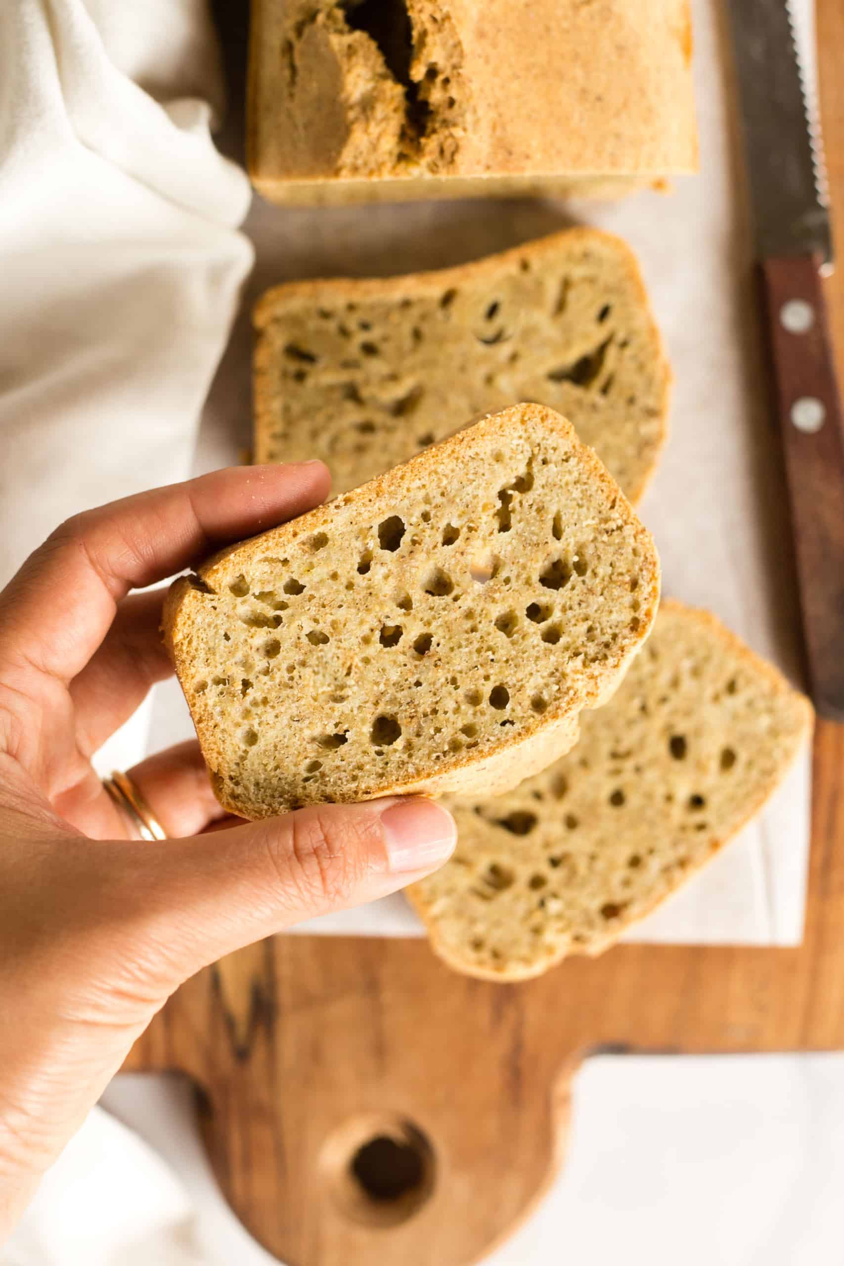 Hand holding up a slice of tiger nut flour bread.