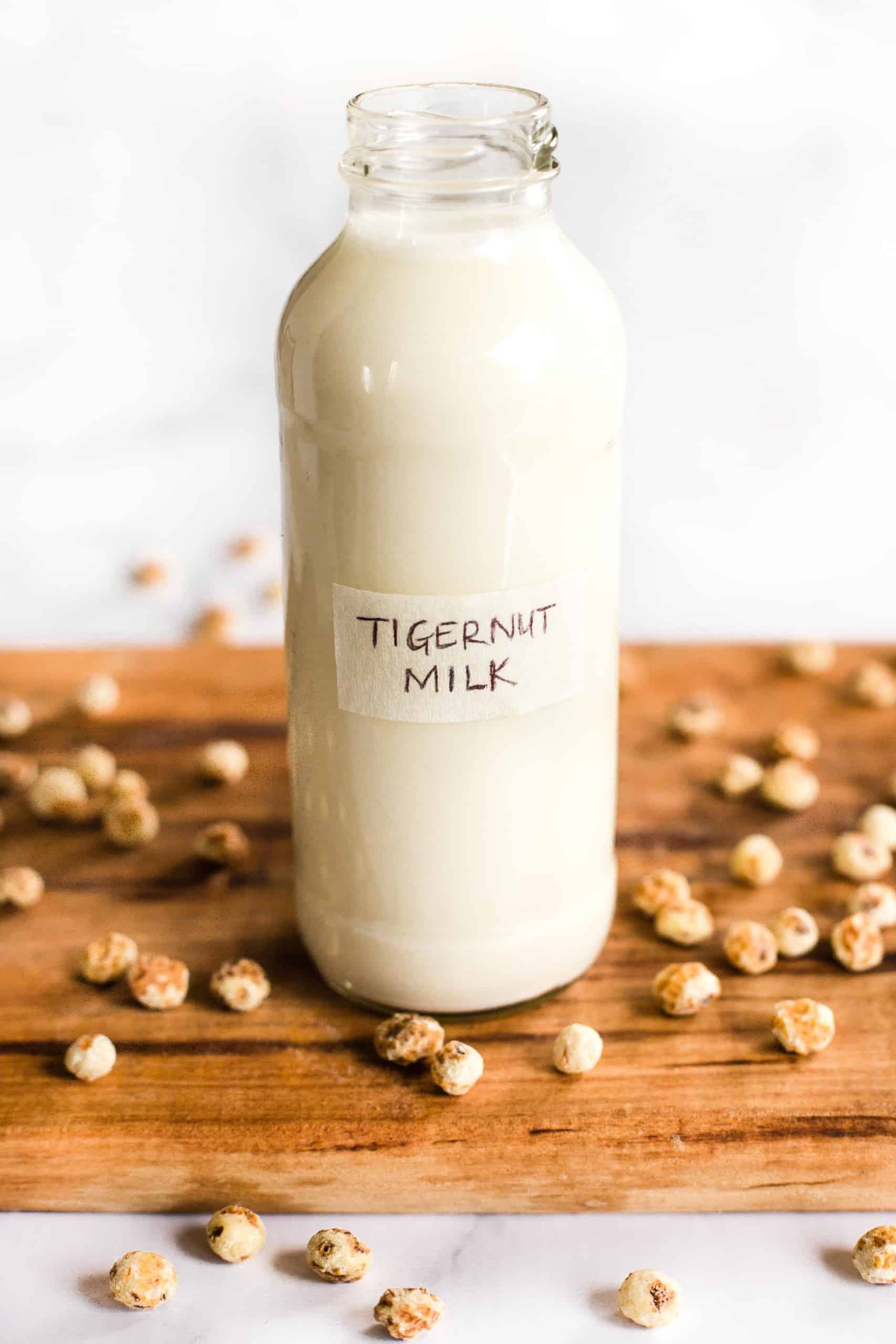 A bottle of homemade tigernut milk and raw tiger nuts on wooden board.