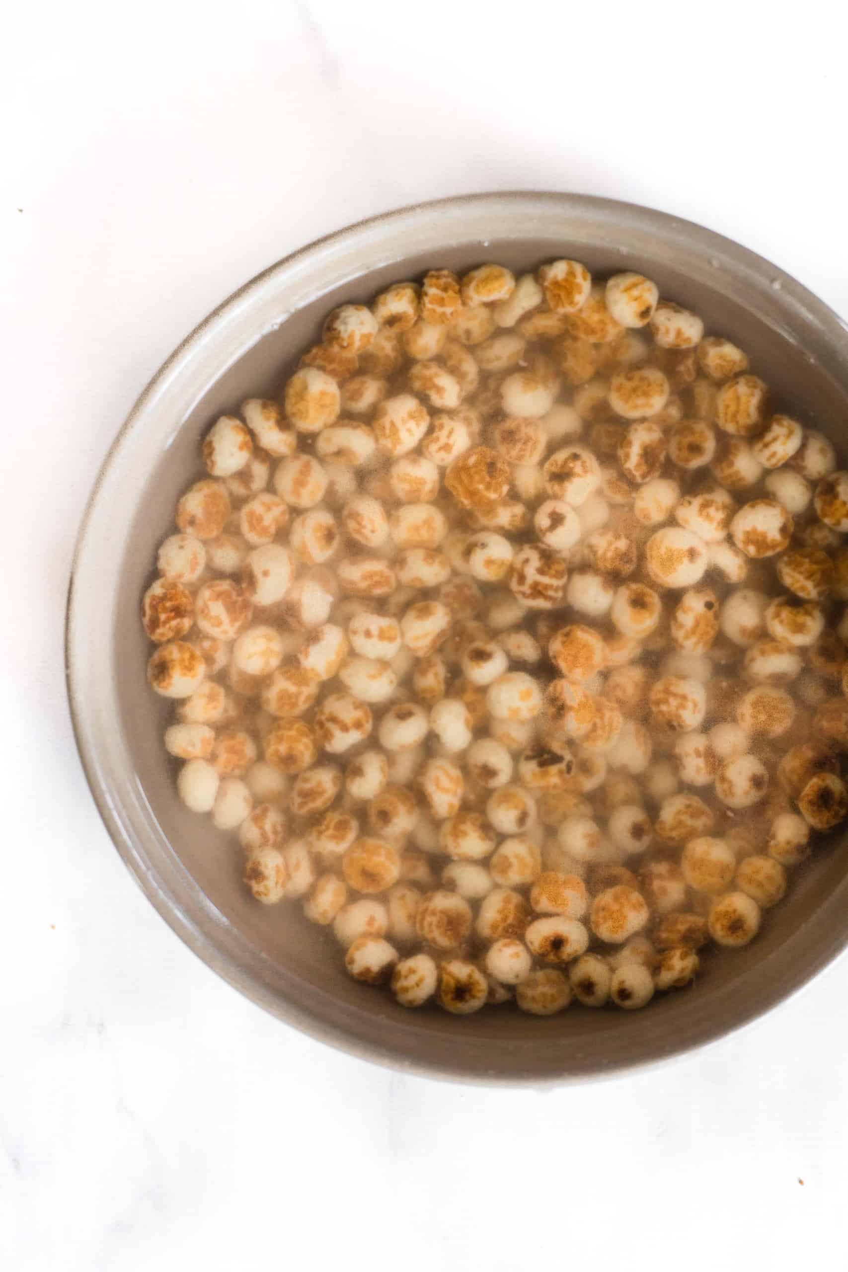 Raw tiger nuts soaking in water in a bowl.