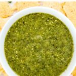 A bowl of tomatillo sauce surrounded by corn nachos