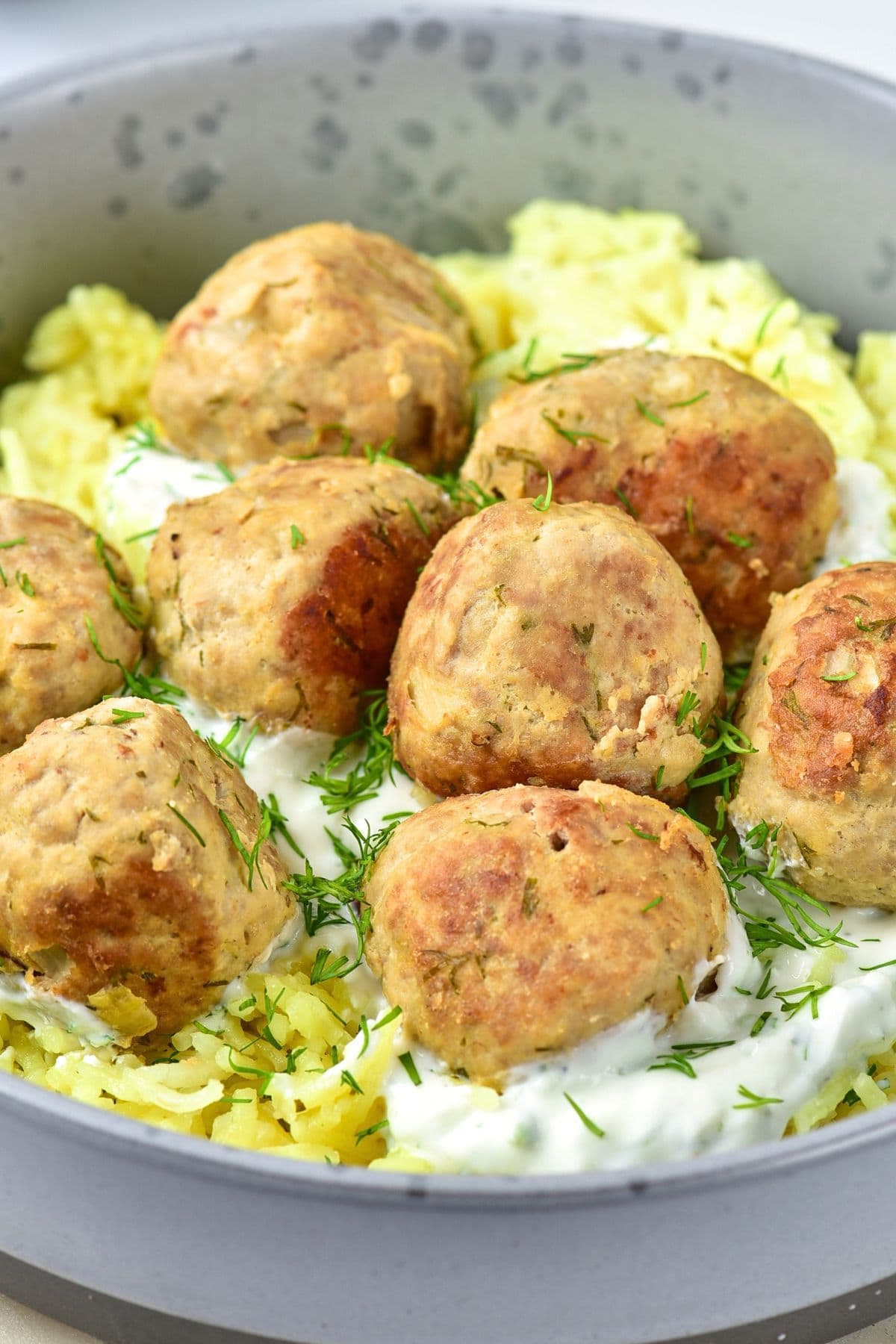 A bowl of turkey feta meatballs over yellow rice.