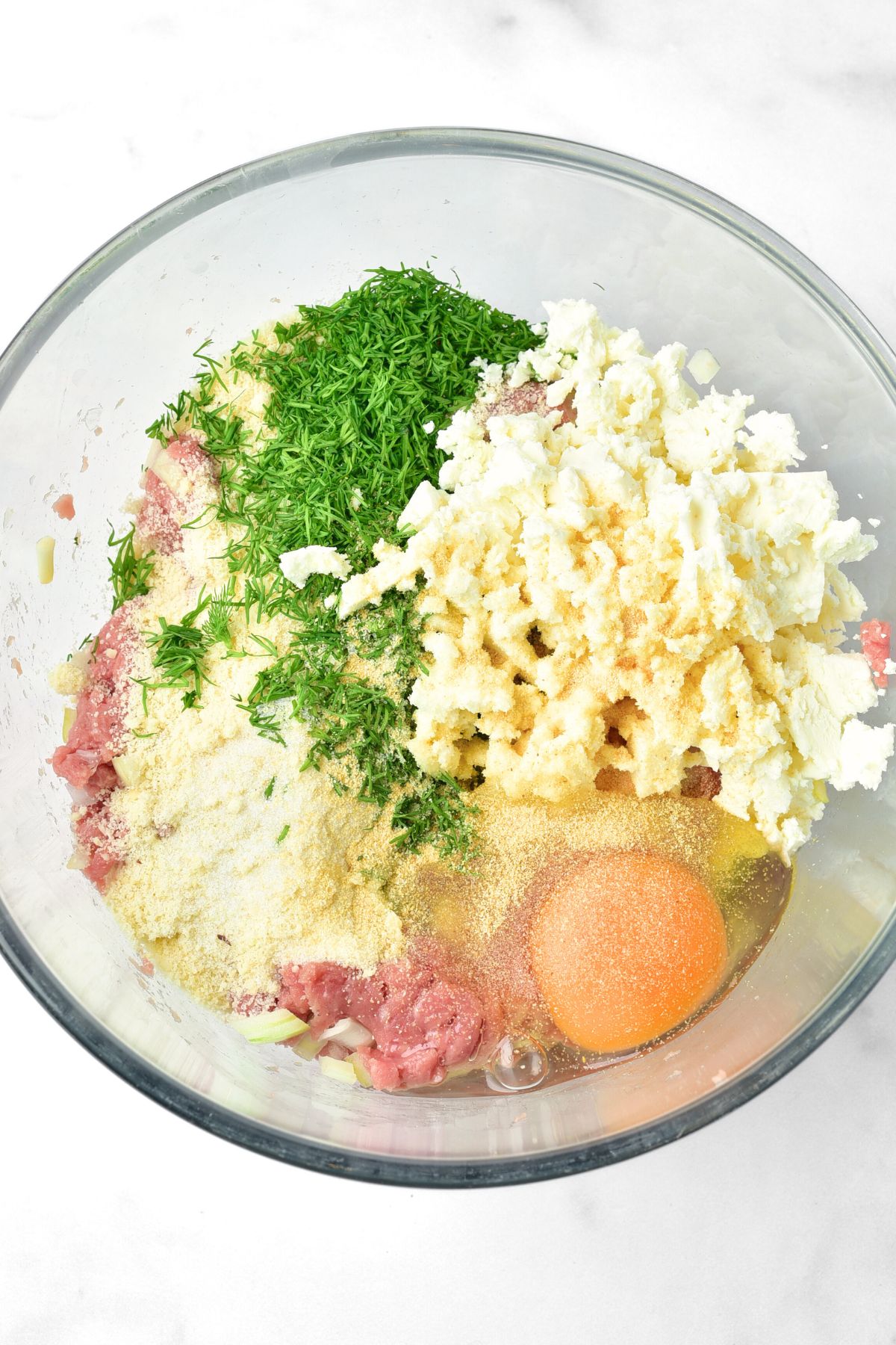 A bowl of ground turkey, almond flour, chopped dill, feta cheese and egg.