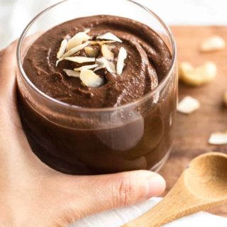 Hand holding a glass of cashew chocolate pudding