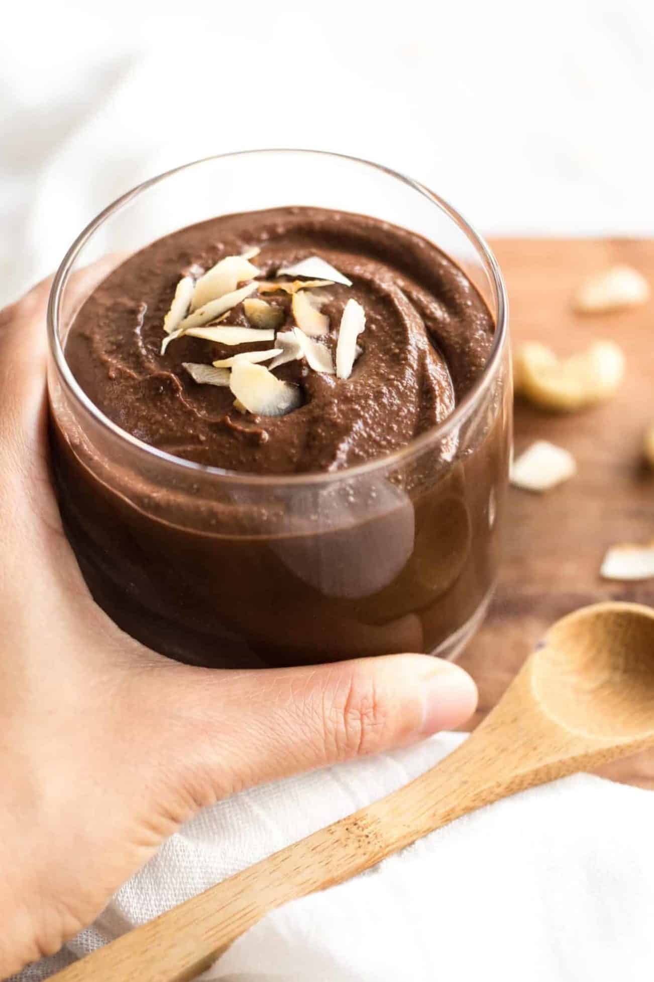 Hand holding a glass of vegan chocolate pudding