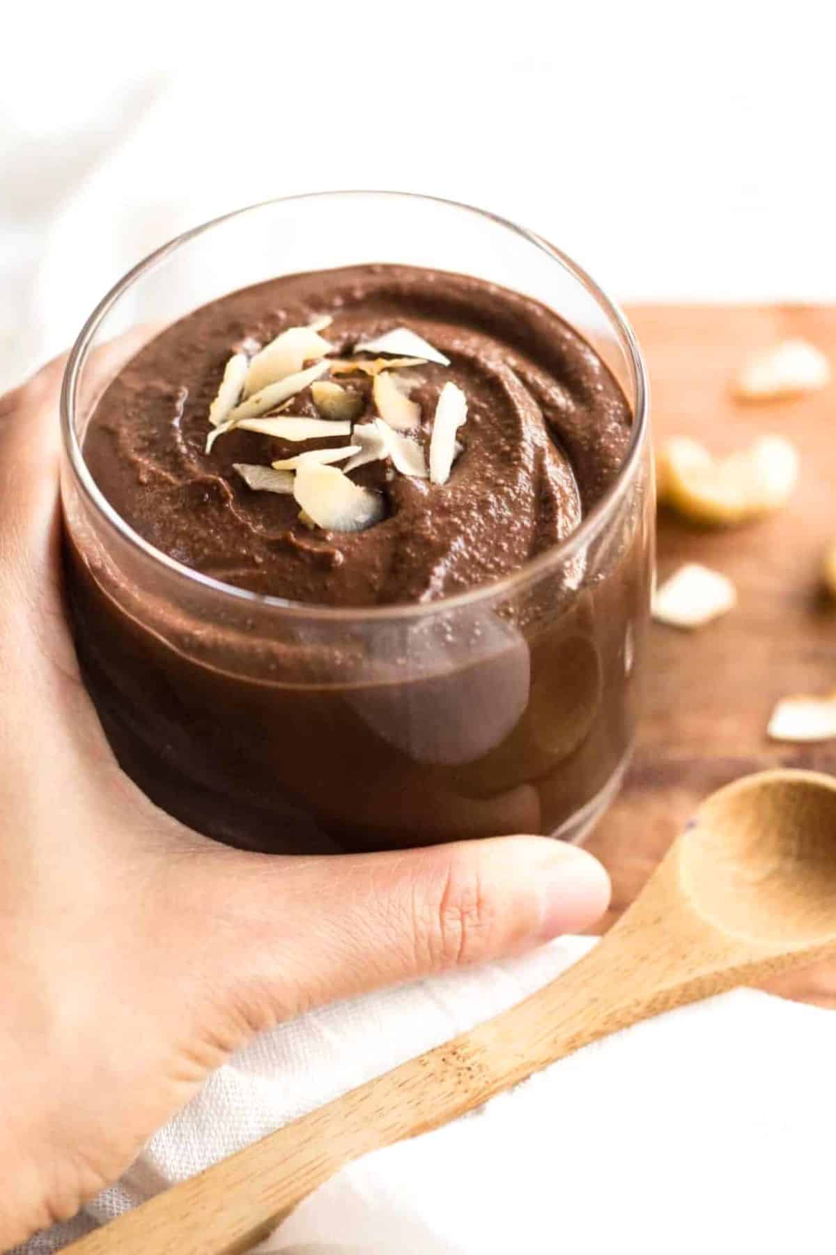 Holding a glass of vegan chocolate pudding.