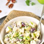A bowl of waldorf salad on parchment-lined tray.
