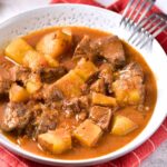A bowl of venison stew on red kitchen towel