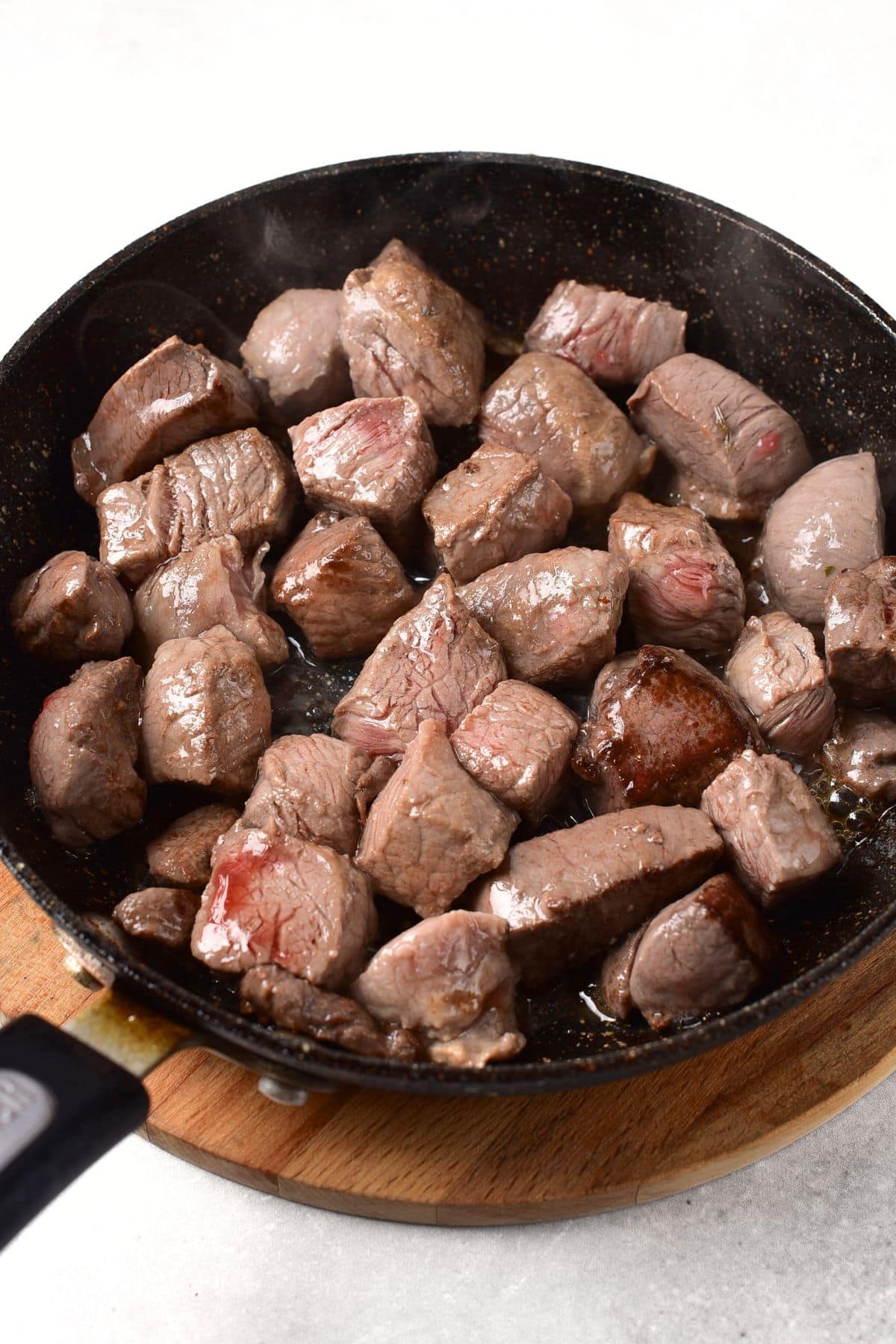 Searing pieces of deer meat in skillet