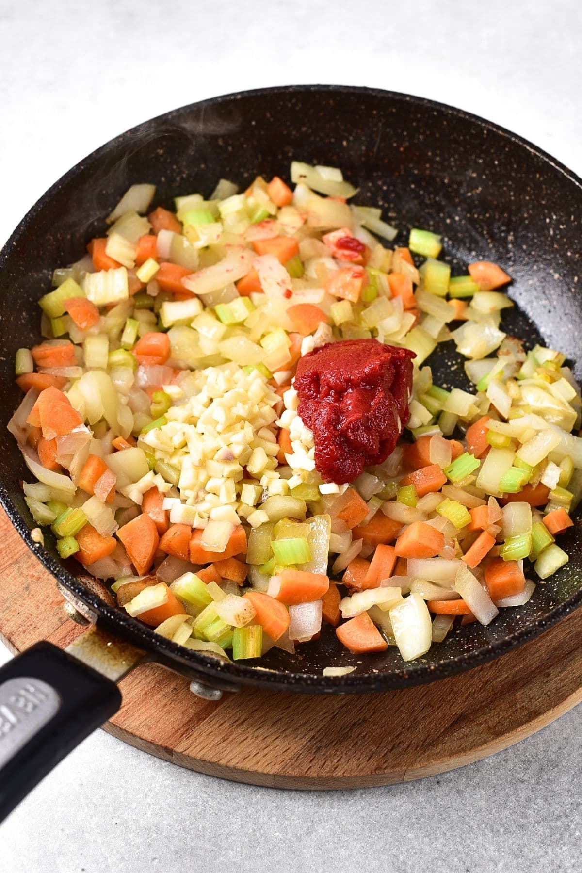 Tomato paste on top of sautéed veggies in skillet