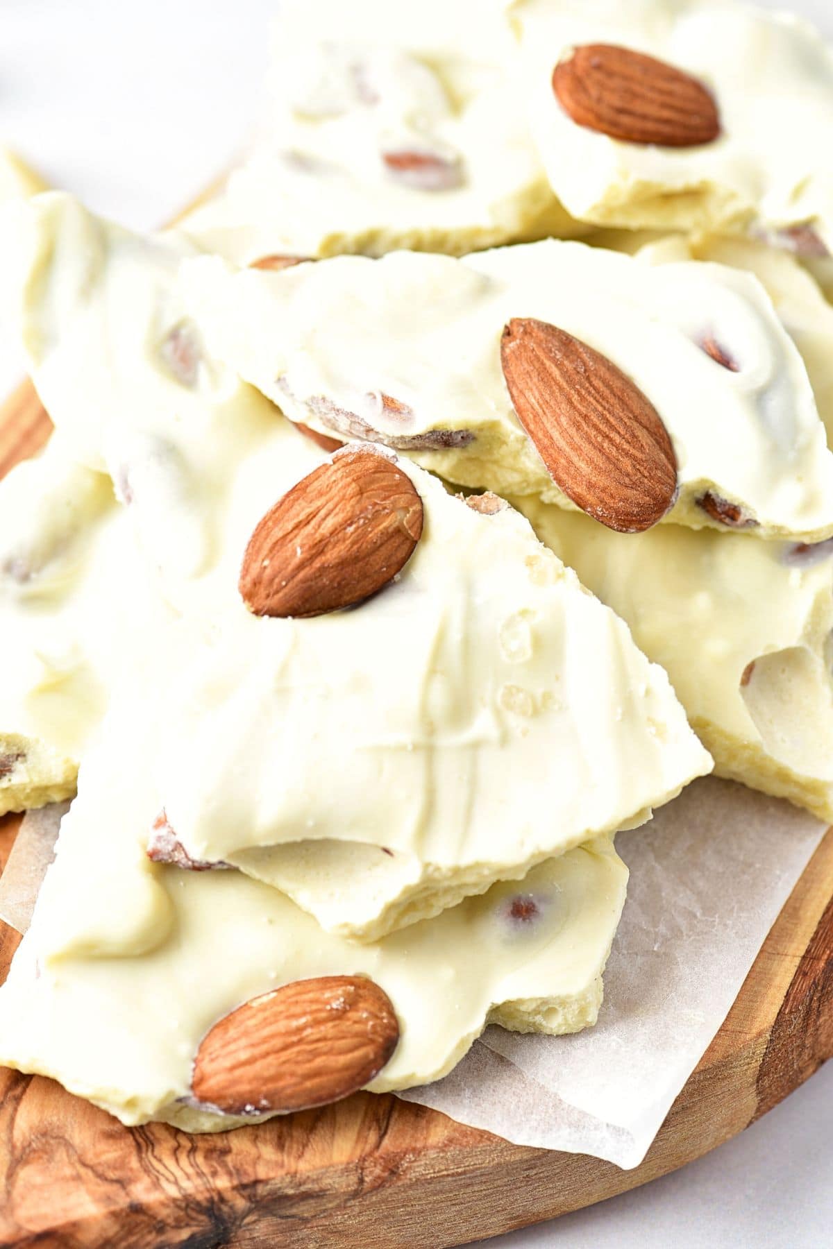 Up close view of almond white chocolate bark on wooden board.