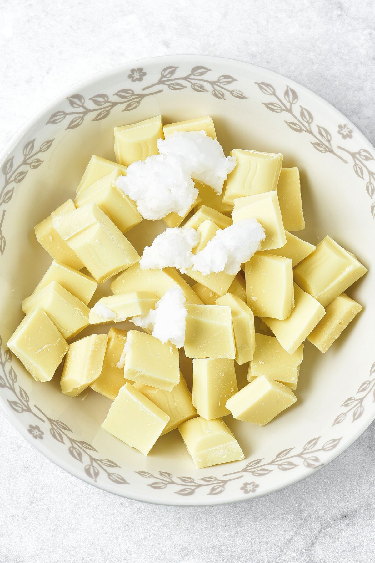 Chopped white chocolate and coconut oil in bowl