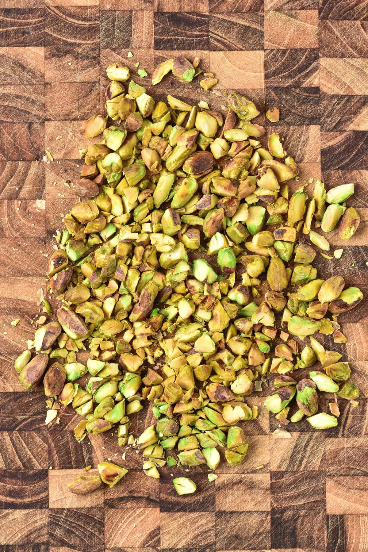 Chopped pistachios on wooden board.