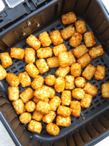 Tater tots in air fryer basket.