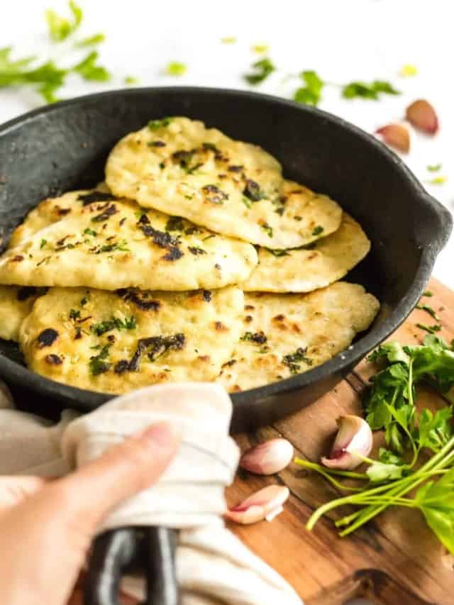 Holding a cast iron skillet with garlic naan.