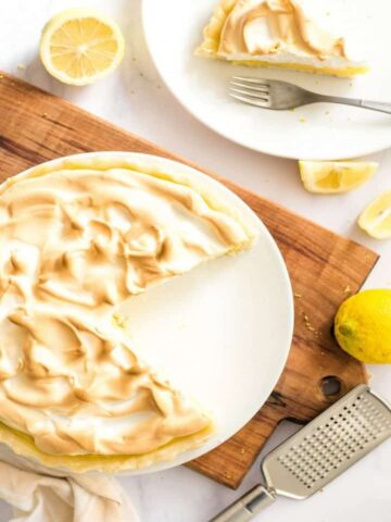 resized image of lemon meringue pie on white plate on wood board