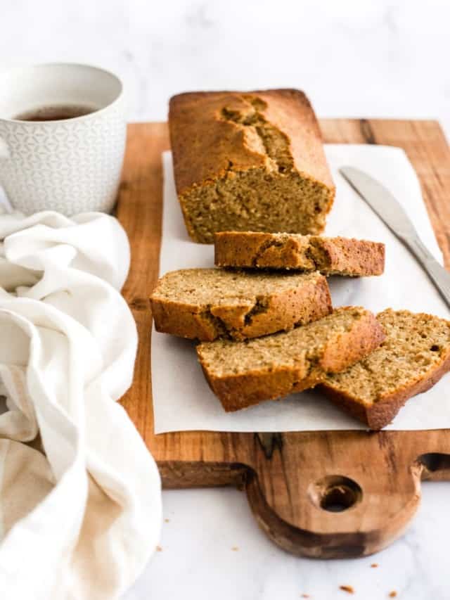 resized image of banana bread loaf and slices on a cutting board with cup of coffee and white towel
